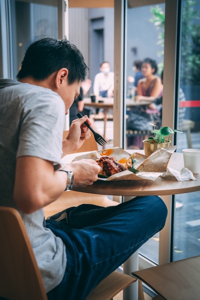 一个穿着灰色t恤的男人坐在椅子上吃饭